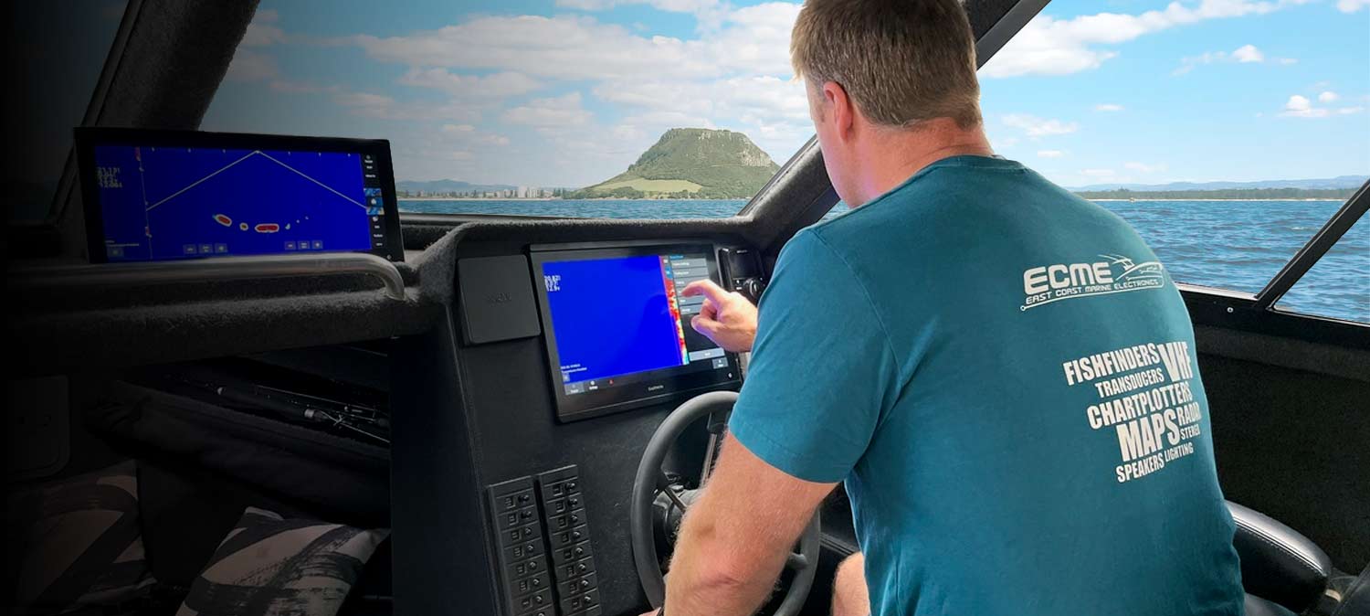 Nigel Louw setting up Garmin electronics on a boat with view of Mt Maunganui in the background.