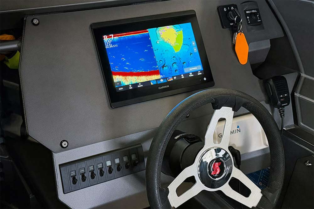 Boat dashboard with a screen displaying sonar graphics and a steering wheel.
